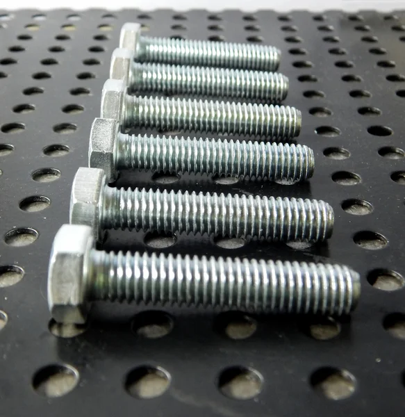 Schrauben und Sechskantmuttern auf Metalloberfläche Nahaufnahme — Stockfoto