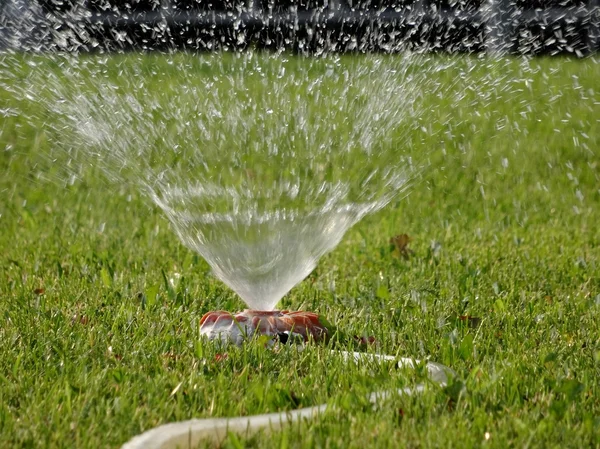 Rasenpflege-Bewässerungssystem bei Arbeiten auf grünem Gras — Stockfoto