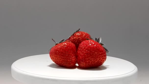 Red juicy strawberry on white plate studio isolated — Stock Video
