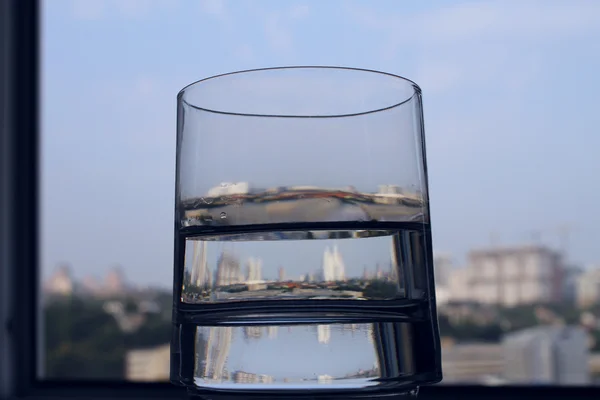 Spiegelung der Stadt in Glas mit klarem Wasser Nahaufnahme — Stockfoto