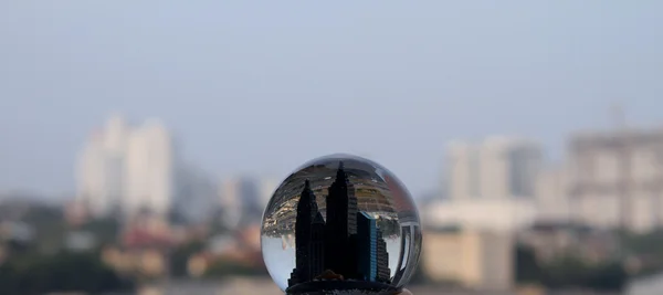 Toy city inside snow globe over real city scape — Stock Photo, Image