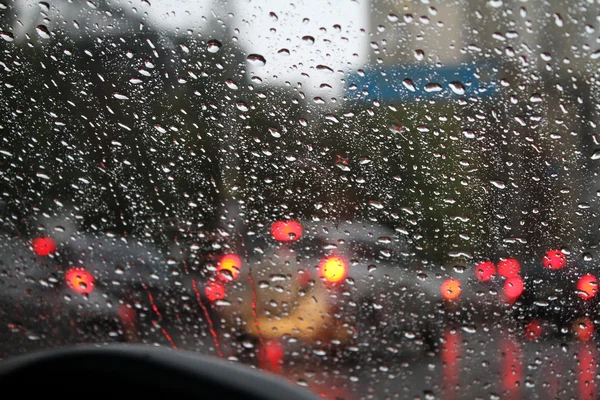 Mira las gotas de agua en el parabrisas del coche desde el interior del coche en la lluvia en la calle de la ciudad —  Fotos de Stock