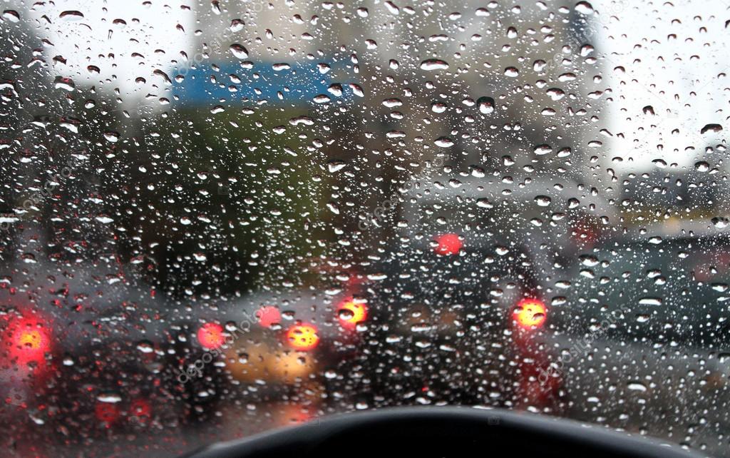 Blick auf die Wassertropfen auf Glas aus dem Auto bei Regen auf der Stadtst...