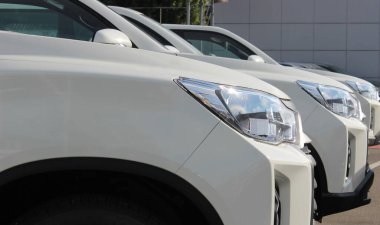 Headlights of same white SUVs lined up at the open air parking 