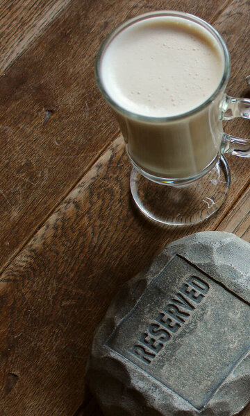Чашка капучино возле традиционной зарезервированной доски на старом винтажном столике кафе 