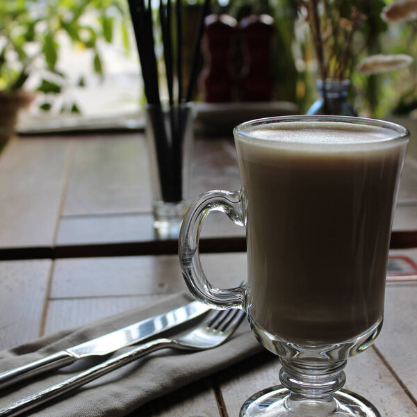 Элегантная стеклянная чашка с кофейной тряпкой на обслуживаемом столе в ресторане, ожидающем клиента