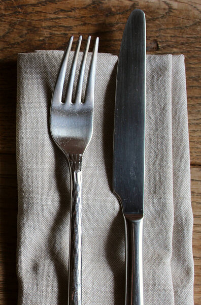 Столовая вилка и нож на домашней салфетке на темном деревянном столе в старом традиционном ресторане