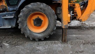 Ağır yüklerle çalışırken destek için çekilebilir hidrolik bacakları olan tekerlekli kazıcı