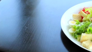 Yeni hazırlanmış ve büyük bir salata tabağında taze malzemelerle servis edilmiş Sezar salatasının panorama videosunu kapat. 