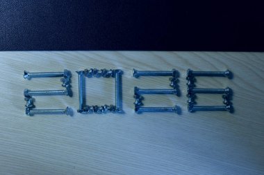 Metal işlemeli cıvatalar ve uğursuz fındıklardan oluşan bir kalıp, üzerinde yazı veya başlık için siyah boşluğun altında 2026 sayısını oluşturur. 