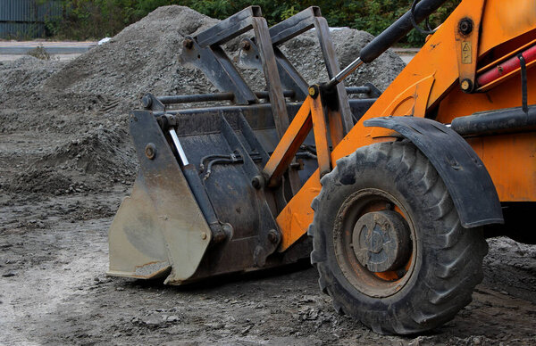 Wheeled Bulldozer with Huge Steel Bucket on a Ground in front of Gravel Heap  