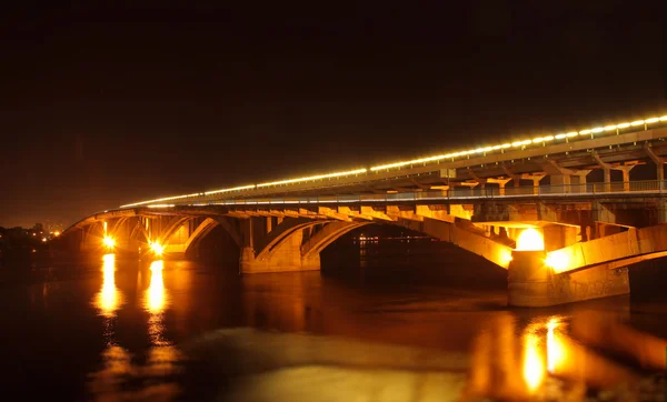 Luzes de rua na ponte sobre o rio refletidas na água à noite — Fotografia de Stock