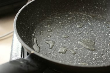 Ocağın üzerine sıcak yağ damlalarıyla granit kaplama mutfak tavası kızarmaya hazır.