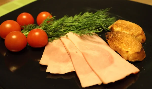 Sliced ham, cherry tomatoes and greens studio isolated — Stock Photo, Image