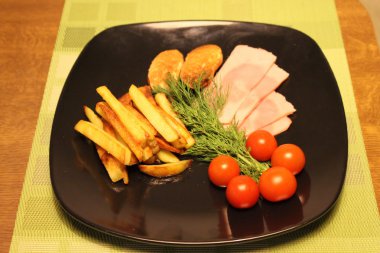 Siyah tabakta kızarmış patates, dilimlenmiş jambon, domates ve yeşillik
