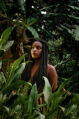 Mujer negra nativa tras plantas