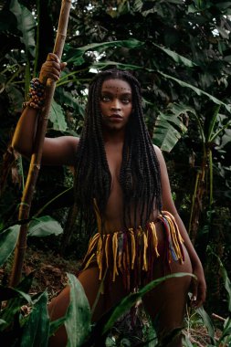 Mujer negra de selva empoderada semidesnuda con mirada hacia arriba