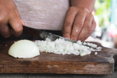 Manos campesinas cortan cebolla en tabla de madera