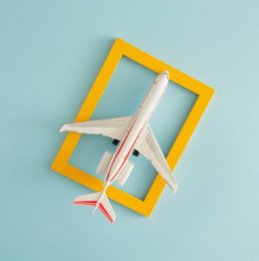 Beyaz, sarı çerçeveli bir uçak. Mavi pastel arka planda retro tarzı. Minimum özgeçmiş. en düşük düzlük