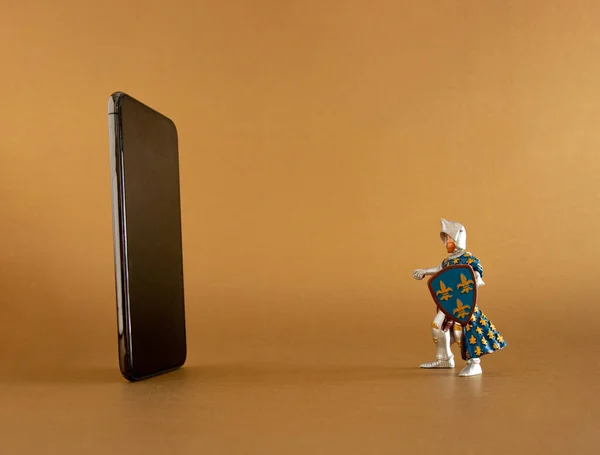 Siyah modern cep telefonu ve altın arka planda eski tarih şövalyesi mavi oyuncak. Soyut sanat. asgari yaratıcı dekorasyon fikri