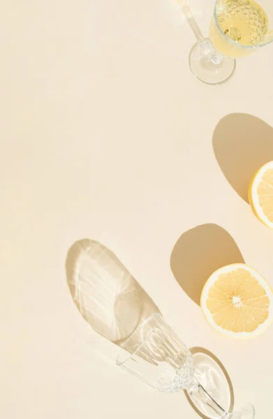 Taze limon ve şarap kadehiyle yazların yaratıcı konsepti, güneşli arka planda gölgeler. Minimum düzlük. Kopyalama alanı olan asgari soyut sanat arkaplanı