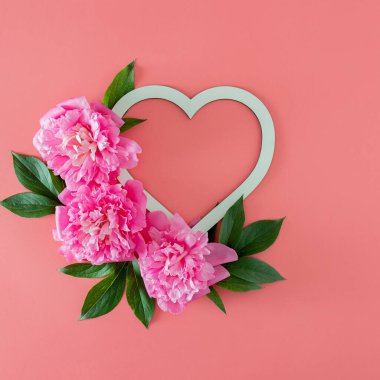 Yeşil yapraklı taze pembe şakayık ve fotokopi alanı olan pembe pastel arka planda çerçeveli. Kopyalama alanı olan asgari tropikal yaz düzlüğü. en küçük bahçe arkaplanı.