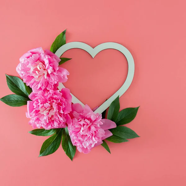 Yeşil yapraklı taze pembe şakayık ve fotokopi alanı olan pembe pastel arka planda çerçeveli. Kopyalama alanı olan asgari tropikal yaz düzlüğü. en küçük bahçe arkaplanı.