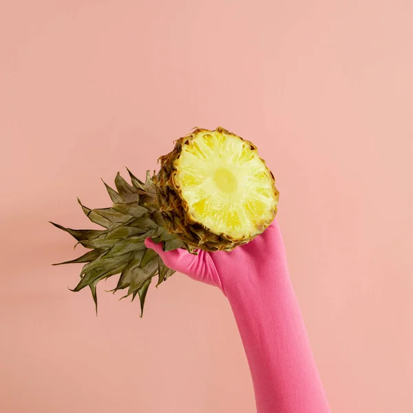 Pembe eldivenli bir el ve pembe güneşli yaz aydınlatma arka planında taze ananas. Soyut sanat. asgari arkaplan fikri.