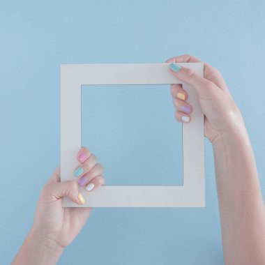 Beyaz çerçeveli, pastel mavi arka planda fotokopi alanı olan bir kadın eli. Soyut sanat. asgari yaratıcı dekorasyon fikri