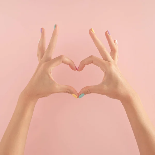 Pastel pembe arka planda renkli tırnakları olan kadın elleri. kopyalama alanı. yaz modern tropikal soyut sanat ve kadın eli. Kopyalama alanı olan en küçük arkaplan fikri