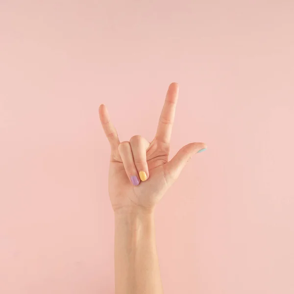 Pastel pembe arka planda renkli tırnakları olan kadın elleri. kopyalama alanı. yaz modern tropikal soyut sanat ve kadın eli. asgari arkaplan fikri.