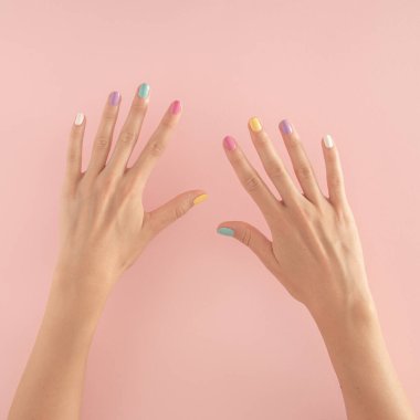 Pastel pembe arka planda renkli tırnakları olan kadın elleri. kopyalama alanı. yaz modern tropikal soyut sanat ve kadın eli. 10 numaralı asgari arkaplan fikri