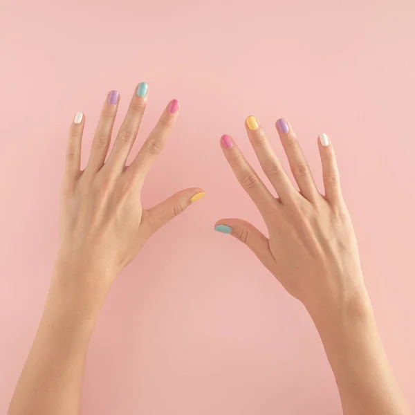 Pastel pembe arka planda renkli tırnakları olan kadın elleri. kopyalama alanı. yaz modern tropikal soyut sanat ve kadın eli. 10 numaralı asgari arkaplan fikri