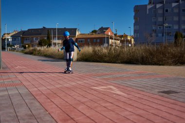 Çocuk kaskla kayıyor ve bisiklet yolunda korunuyor. Kendini korumak için maske takıyor.