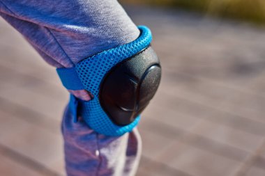 Diz için siyah ve mavi paten giyen bir çocuk.