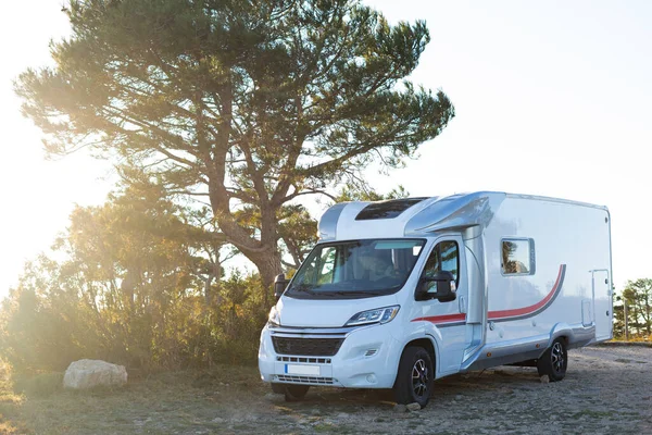 Camper van parked at a spanish mediterranean forest. The picture is taken at the golden hour. The van is ready as a camp site.