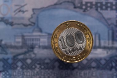Kazakistan Cumhurbaşkanı 'nın Nur-Sultan' daki ikametgahını gösteren 20.000 'lik bir banknotun arka planına karşılık 100 Kazakistan madeni parası.