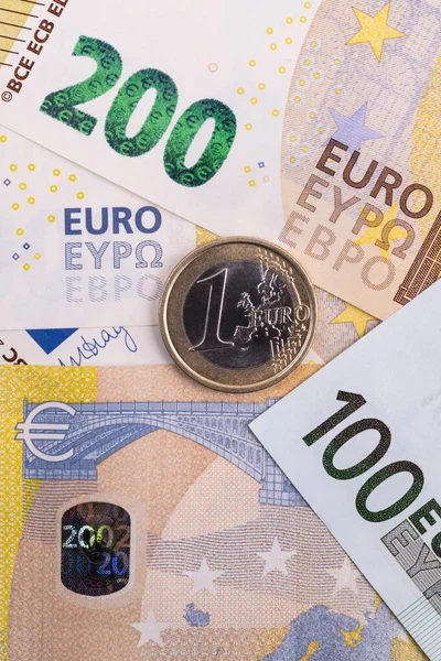 200欧元和100欧元钞票背景下的一枚欧元硬币 — 图库照片