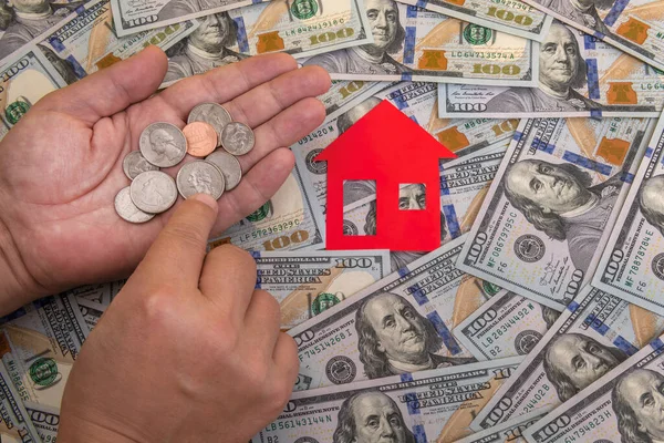 American coins in hands, red house and 100 American dollar bills