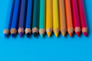 Arka planda mavi bir yaprak üzerinde ahşap renkli kalemler.