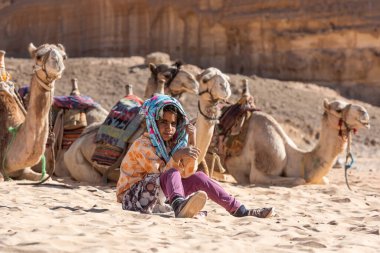 Sharm El Sheikh, Mısır, 02 / 05 / 2018. Bedevi bir kız, Sina Çölü 'nde kumsalda oturuyor. Develer geleneksel koşum takımlarıyla turnuva için bekliyor.