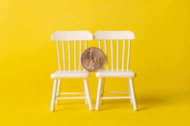 Bir Amerikan doları değerinde bir sikke, sarı arka planda iki oyuncak parçasında kenarda durur.