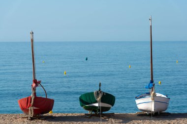 Sabahın erken saatlerinde kumlu sahilde üç küçük eğlence teknesi.