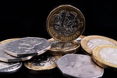 1 İngiliz poundu ve siyah arkaplanda diğer İngiliz paraları