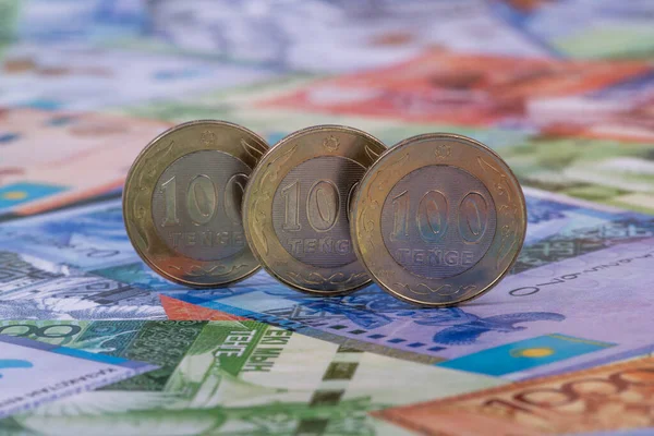 Kazakistan 'ın çeşitli banknotlarının arka planına karşılık 100 Kazakistan' a ait üç adet bozuk para.
