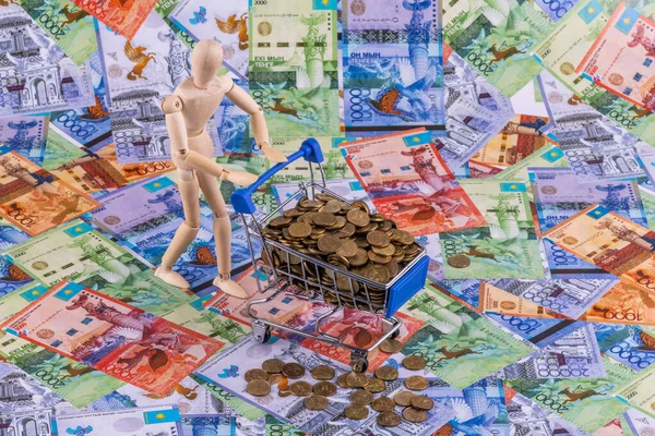 Bir süpermarketten minyatür bir alışveriş arabası, 1 tenge bozuk para yığını ve çeşitli mezheplerden Kazakistan banknotları.