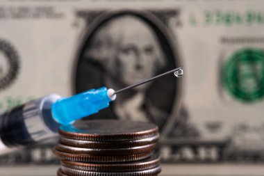 Tek kullanımlık şırınga şırıngası. Ucunda bir damla sıvı olan şırınga. Amerikan dolarının bir parçasının arka planına karşı.