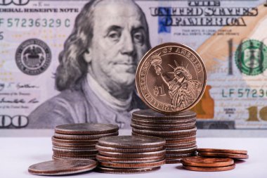 100 dolarlık banknotun arka planına karşılık 1 Amerikan dorllar madeni parası.