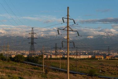 Dağın eteğindeki şehrin arka planında yüksek voltajlı iletim hatları var.