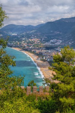 Arka planda bir ortaçağ şatosunun kale duvarı ve Türkiye 'nin Alanya kenti yer alıyor.